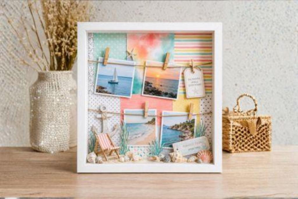 Shadow-Box mit Fotos von Segelboot, Sonnenuntergang und Strand, Dekoration mit Muscheln, Miniatur-Strandstuhl und Pflanzen in weißem Rahmen
