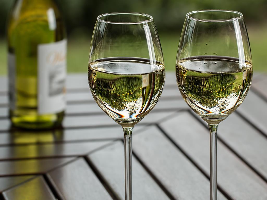Zwei halbvolle Weingläser,die auf einem dunklen Holztisch stehen.