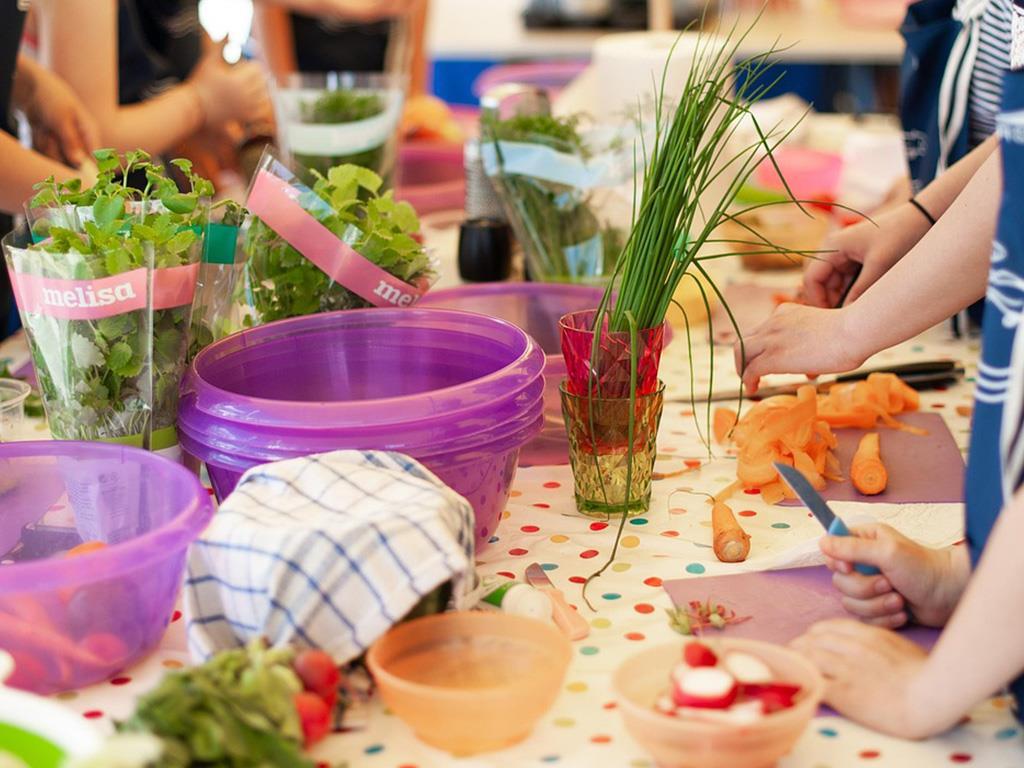 Kinder koch gemeinsam mit verschiedenem Gemüse an einem Tisch.