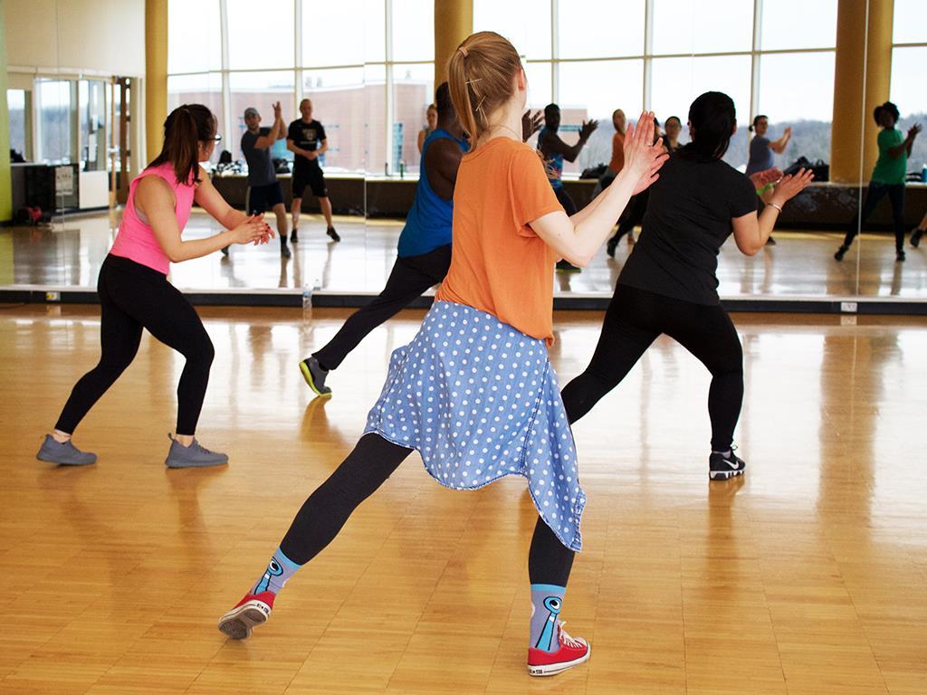 Eine Gruppe tanzender Menschen steht vor einem Spiegel.