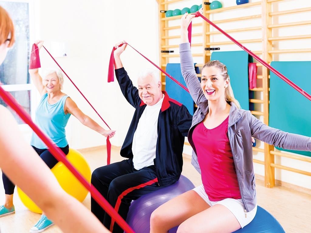 Menschen verschiedener Altersgruppen machen gemeinsam ein Workout mit Therabändern.