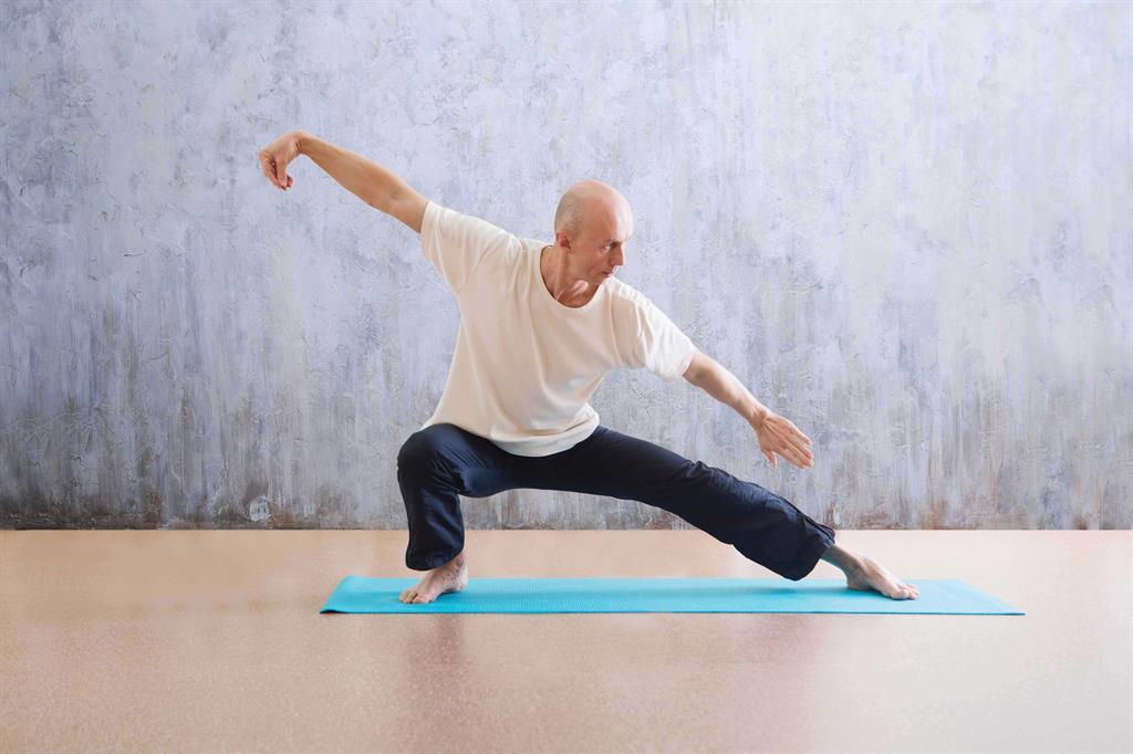 Ein Mann macht eine kriegerähnliche Yogafigur.