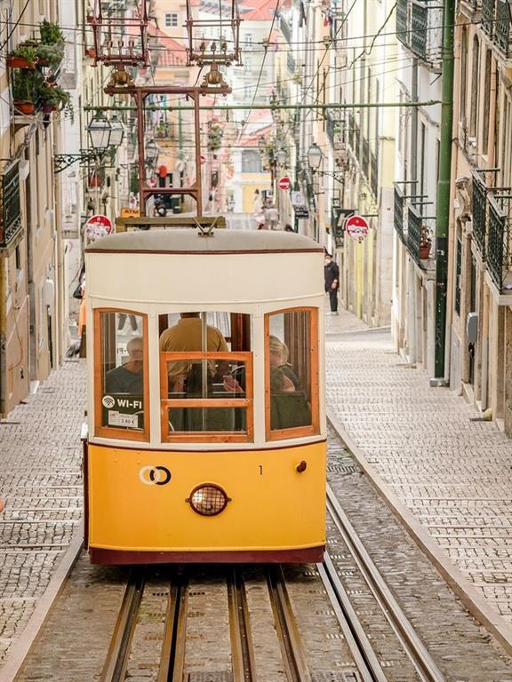Klassische gelbe Straßenbahn fährt durch eine Stadt in Portugal
