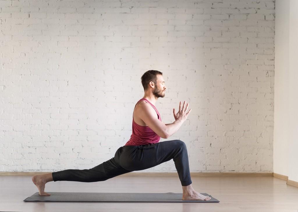 Ein Mann führt die Krieger Yogapose aus.