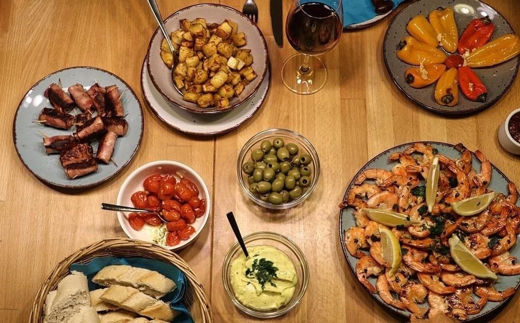 Verschiedene Tapas wie Oliven, Garnelen, Paprika und viele weitere auf einem Tisch angerichtet.