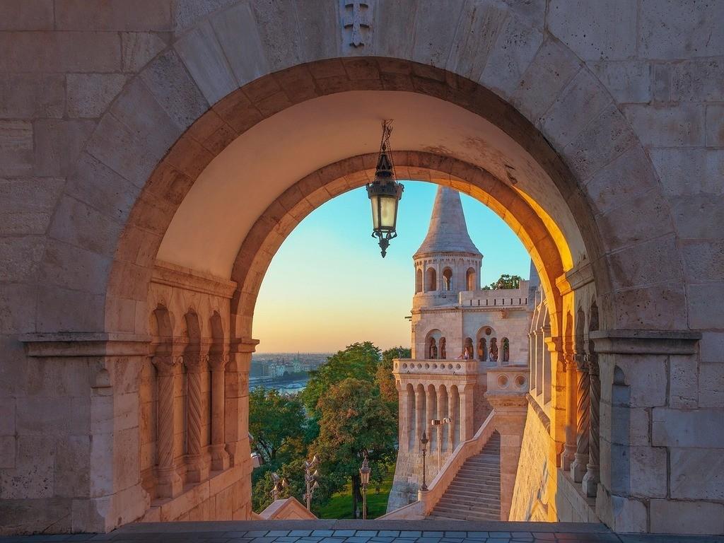 Blick durch einen historischen Torbogen auf eine Kirche in Budapest.